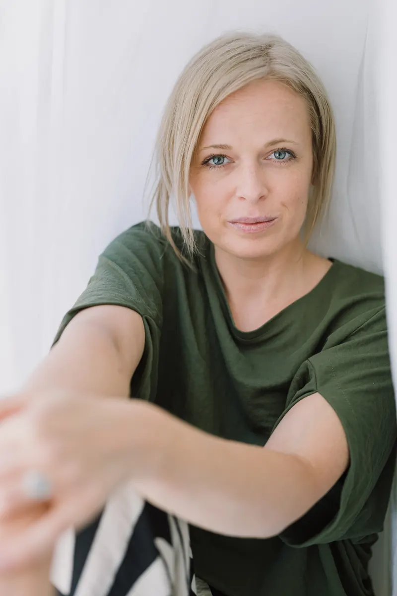 Precub Mária egyenesen a kamerába néz, nyújtott kézzel, zöld pólóban.